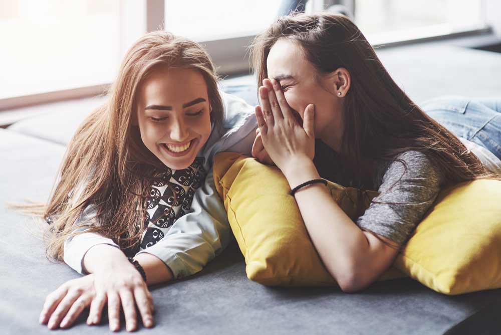 Two beautiful young twins sisters spending time together with pillows.