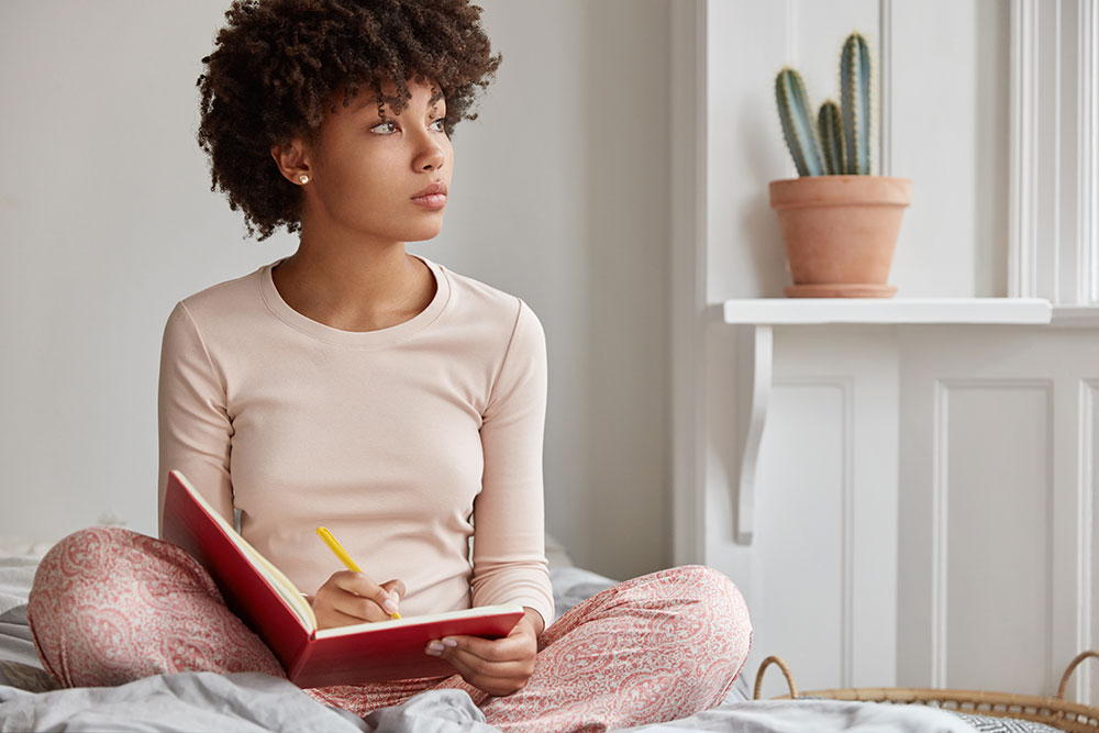 A girl journal on bed.